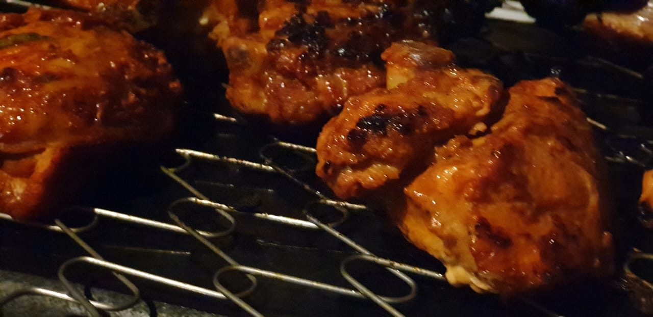 Chicken roasting on a grill over glowing coals