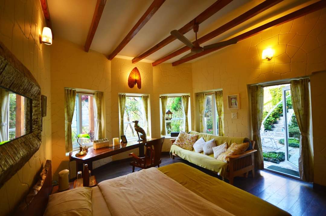 Warm bedroom with beamed ceiling, a row of curtained windows and a glass door opening outside