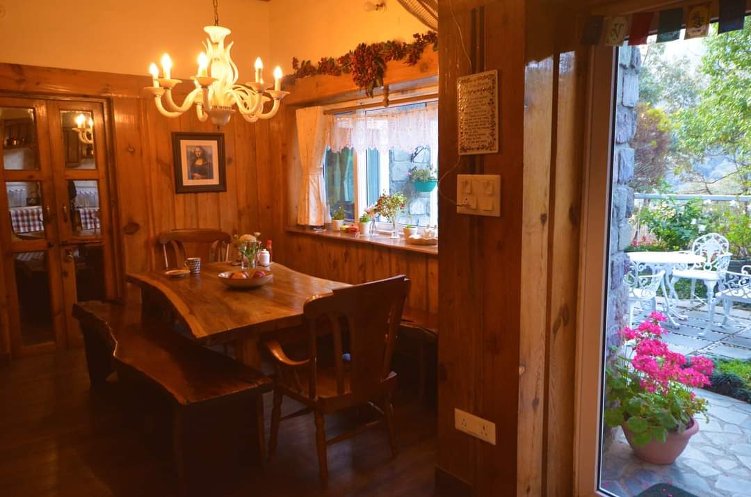 Wood-panelled dining room with a chandelier, a solid wood table and a door open to the garden