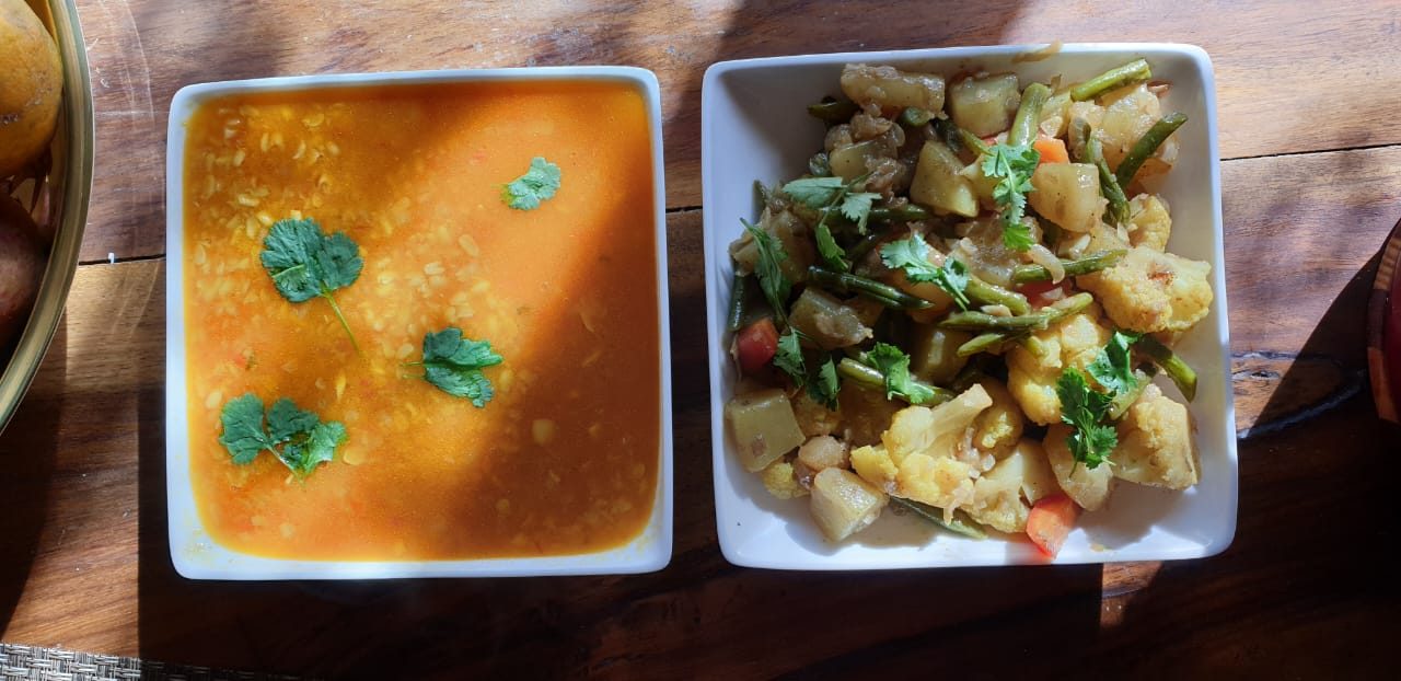 Bowls of dal and a vegetable sabzi on a wooden table